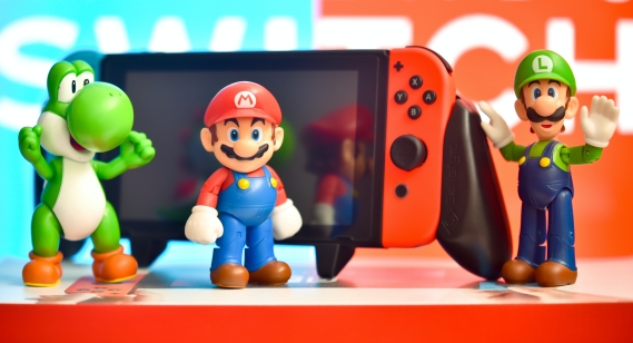 Super Mario characters standing in front of a Nintendo Switch